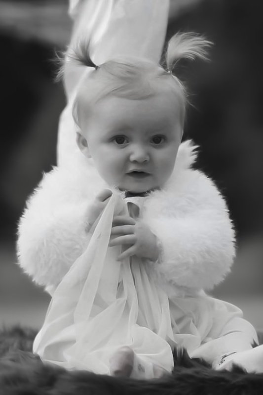 Litet barn i vit fäll porträtterat av Sofia Borg Fotografi, naturligt ljus och varm ton.